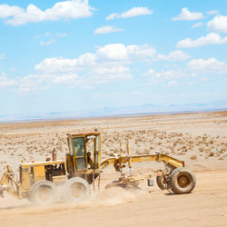 Tractor on sand against sky