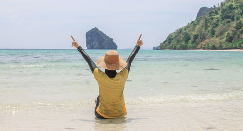 Rear view of woman gesturing while at beach