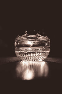 Close-up of illuminated lamp on table against black background