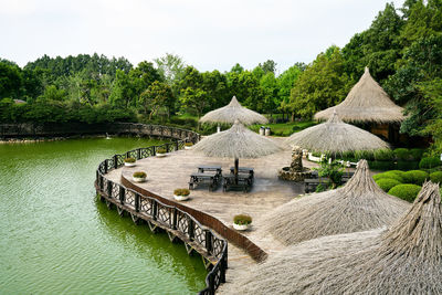 Thatched roof on pier over lake against trees