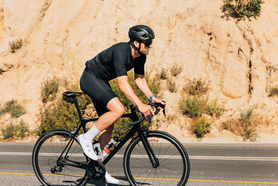 Rear view of man riding bicycle on road