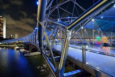 Illuminated bridge over river in city at night