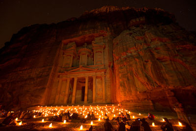 People at illuminated temple against building at night