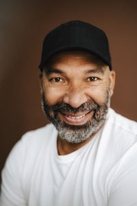 Smiling man with cap against brown background