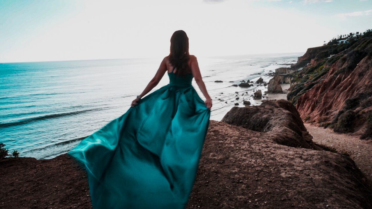 REAR VIEW OF WOMAN STANDING ON BEACH