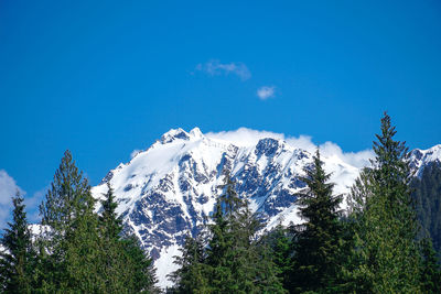 Low angle view of snowcapped mountains against blue sky