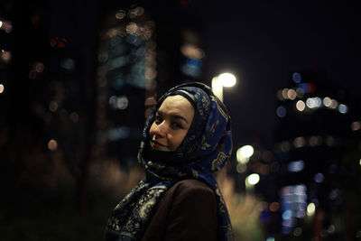 Portrait of woman wearing hijab in city at night