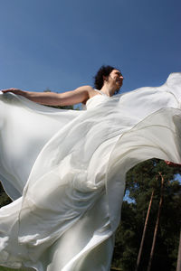 Low angle view of woman against blue sky