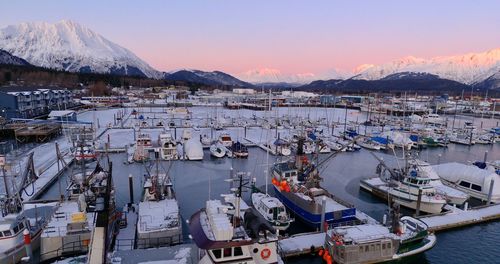 Sailboats moored at harbor against sky during sunset