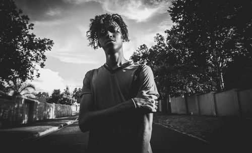 Rear view of young man standing by tree against sky