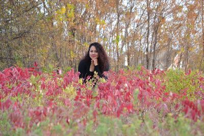 Portrait of woman amidst plants and trees during autumn