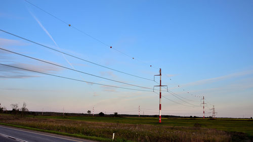 Electricity pylons on field against sky