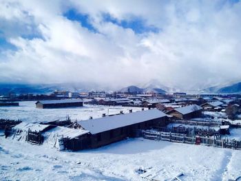 Snow covered landscape against cloudy sky