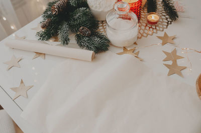 Christmas table decor, roll of baking paper, burning candles, christmas tree twigs and paper stars