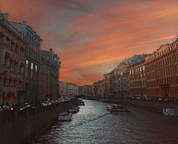 Canal amidst buildings against sky during sunset