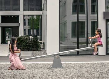 Side view of woman sitting on sidewalk