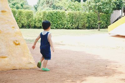 Rear view of boy walking on street amidst trees