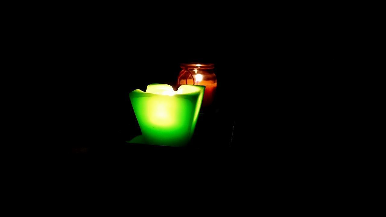 CLOSE-UP OF ILLUMINATED TEA LIGHT CANDLE IN DARKROOM