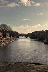 River amidst buildings in city against sky