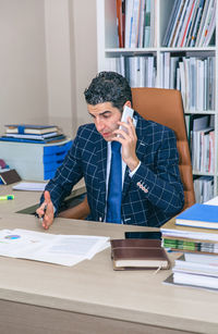 Young man using mobile phone while sitting on table