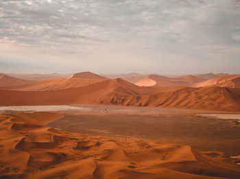 Scenic view of desert against cloudy sky