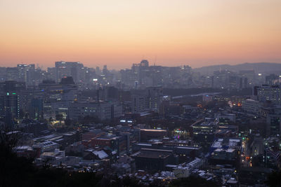 Illuminated cityscape against clear sky during sunset