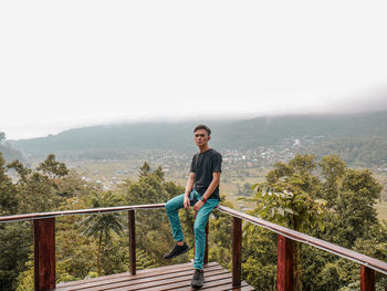 Full length of young man on railing against sky