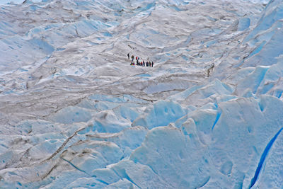 High angle view of people hiking on snow covered mountain