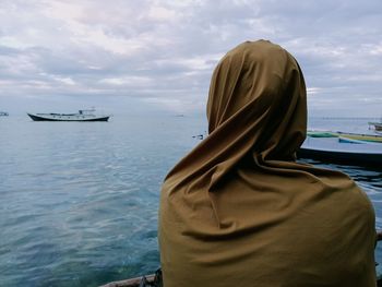 Rear view of woman on boat in sea against sky