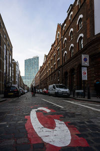 Cars on road in city against sky