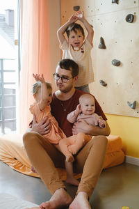 Happy father with tree small kids playing at home. dad cuddling with children, holding them on hands