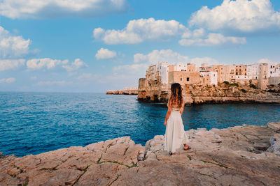 Woman by sea against sky