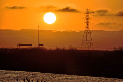 Silhouette electricity pylon against sky during sunset