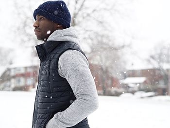 Side view of mid adult man standing on snow covered field during winter