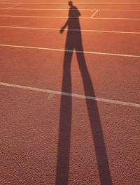 Shadow of man walking on running track