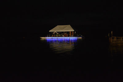 Illuminated building by lake against clear sky at night