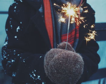 Midsection of person with illuminated sparkler