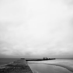 Pier by sea against cloudy sky