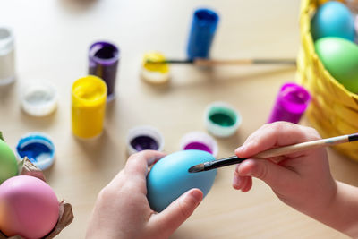 Little child hands painting colored eggs. easter family holiday at home and craft concept.