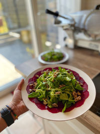 Person holding salad in plate on table