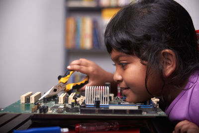 Little girl playing with motherboard computer at home