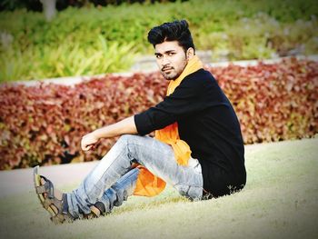 Portrait of young man sitting on land