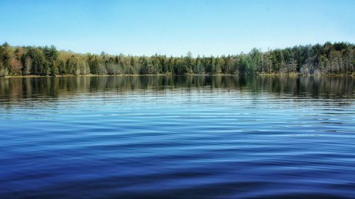 Calm lake against clear blue sky