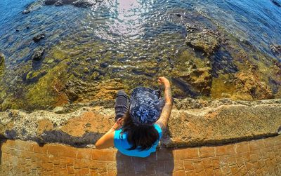 Rear view of woman sitting on pier against sea