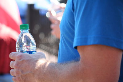 Close-up of man holding bottle in water