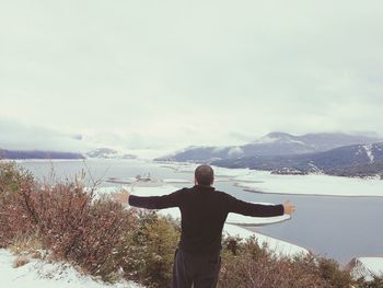 Rear view of man standing by sea against sky