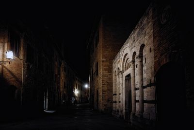 Illuminated street amidst buildings at night