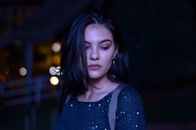 Beautiful young woman standing outdoors at night