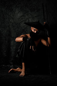 Full length portrait of woman wearing hat against black background