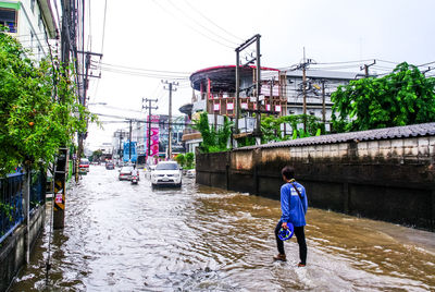 Rear view of man with umbrella in city during rainy season